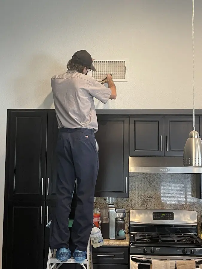 Technician inspecting an air vent during HVAC service in Calverton